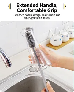 Detailed view of a grey silicone bottle brush cleaning a tall glass over a kitchen sink