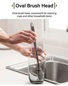 Close-up of grey silicone bottle brush with long handle cleaning a glass bottle in sink