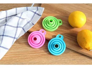 Gros plan de trois entonnoirs en silicone pliables et colorés sur une planche avec citrons.