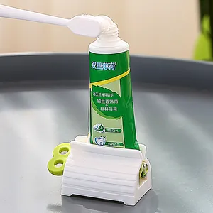 Handmatige plastic tandpasta-uitperser met draaiende groene sleutel en witte houder