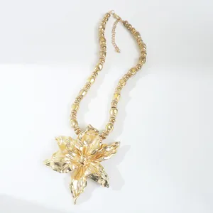 Detailed view of large golden metallic flower pendant on a beaded choker necklace.