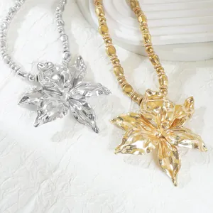 Close-up of gold and silver metallic chunky flower necklaces on textured background
