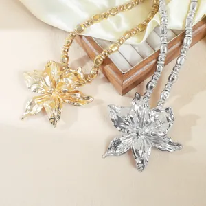 Detail of gold and silver alloy floral necklaces with bold metallic lily pendants.