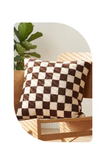 Close-up of a brown and white checkerboard sherpa throw pillow on a wooden chair.