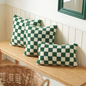 Three green and white checkered sherpa fleece throw pillow covers on a wooden bench