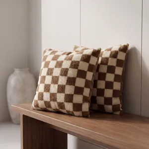 Cozy brown and cream checkerboard sherpa fleece throw pillow covers on a wooden bench
