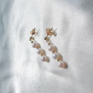 Primo piano di eleganti orecchini pendenti con perle naturali placcati oro 18K