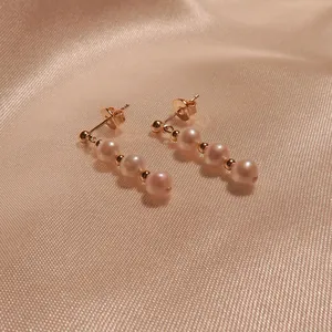 Elegante primo piano di orecchini a pendente con perle naturali d'acqua dolce in oro 18K
