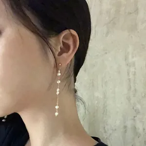 Dettaglio di eleganti orecchini pendenti lunghi con perle d'acqua dolce naturali su una modella