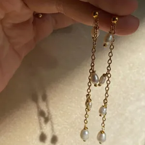 Primo piano di orecchini a catena d'oro con diverse perle naturali d'acqua dolce