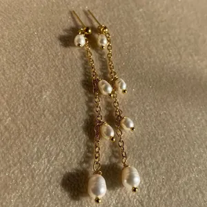 Dettaglio di orecchini pendenti con perle d'acqua dolce naturali e placcatura oro 18K