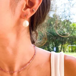 Primo piano di eleganti orecchini pendenti con perle d'acqua dolce naturali all'aperto