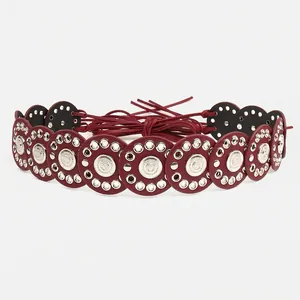 Close-up of bohemian red leather circle belt with silver rivets and embossed sun patterns