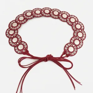 Detail view of a Bohemian red leather belt with metallic disc accents and a bow knot