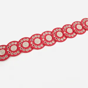 Close-up detail of bohemian red leather belt with silver grommets and round discs