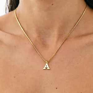 Close-up of a gold titanium steel necklace with a capital letter A pendant on a model
