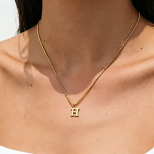 Elegant close-up view of a golden stainless steel letter H pendant necklace on neck