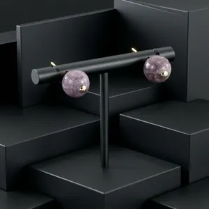Detail view of purple semi-precious stone stud earrings with gold-plated metal caps.