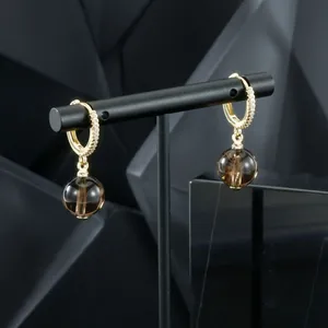 Detailed view of gold-plated hoop earrings with smoky brown gemstone drops and zircons.