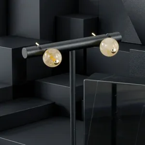 Detail view of round yellow quartz ball earrings on a minimalist black display stand