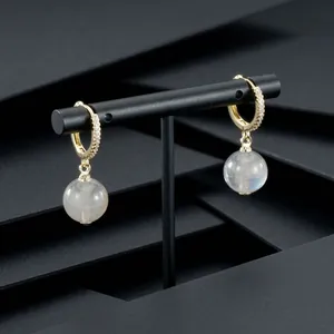 Detail of gold-plated hoop earrings with pavé crystals and sphere moonstone pendant