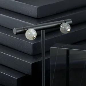 Detail view of spherical semi-precious stone earrings on black professional stand