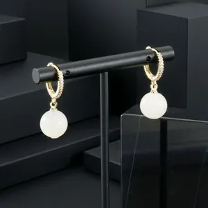 Close-up of gold-plated zircon hoop earrings with white semi-precious stone drops