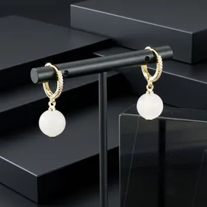 Detail view of gold-plated hoop earrings featuring CZ inlay and white round stone drop