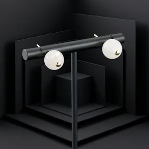 Detail of gold-plated earrings featuring elegant white spherical stones on a black stand