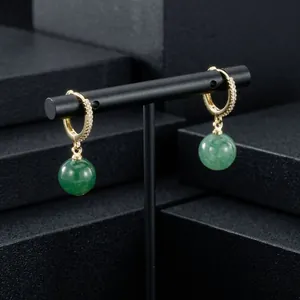 Detail view of gold-plated hoop earrings with green semi-precious stone spheres
