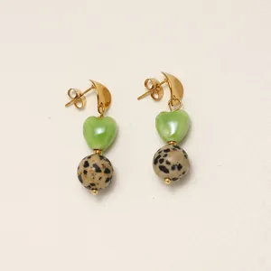 Gros plan de perles vertes en forme de cœur et de boucles d'oreilles en jaspe dalmate dorées.