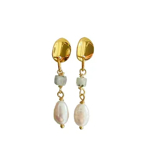 Gros plan de boucles d'oreilles dorées avec pierre naturelle verte et perle d'eau douce.