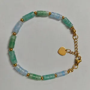 Detalle de pulsera de cuentas de piedra natural con un dije de corazón dorado