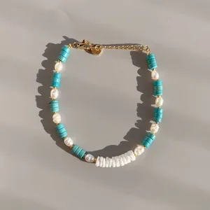 Vista detallada de una pulsera de cuentas bohemia con tubos turquesas y perlas blancas.