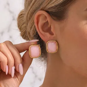 Elegant pink resin stud earrings with gold-plated stainless steel finish shown on model