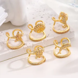 Detailed macro shot of gold plated nail rings featuring sparkling marine animal motifs.