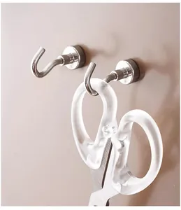 Detailed view of silver magnetic metal hooks holding translucent scissors on a wall