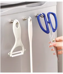 Close-up of powerful magnetic metal hooks holding kitchen utensils on refrigerator