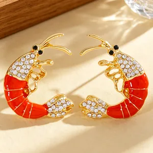 Macro detail view of elegant red enamel shrimp earrings decorated with sparkling rhinestones.