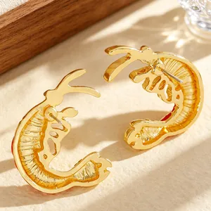 Macro shot of gold lobster stud earrings with detailed red enamel and metal texture.