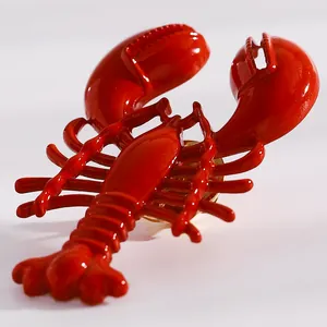 Close-up detail of a vibrant red lobster pendant earring featuring a glossy enamel finish.