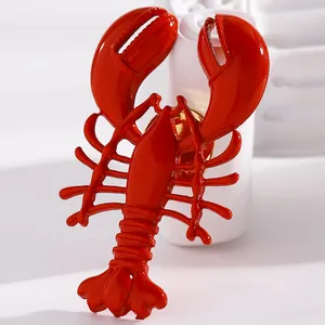 Close-up of vibrant red alloy lobster pendant earring with detailed texture and gloss.