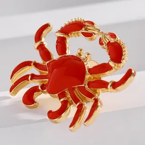Close-up detail of a vibrant red enamel crab brooch featuring elegant gold-tone alloy finish