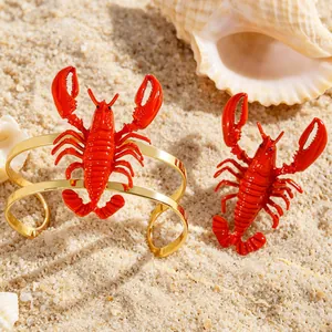 Stunning macro detail of red lobster cuff bracelet and matching earring set on beach sand