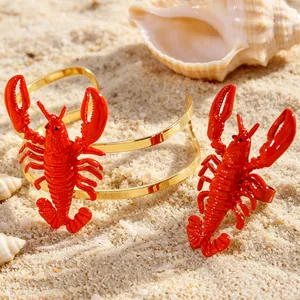 Detailed view of vibrant red lobster bracelet and ring set on beach sand with shells.