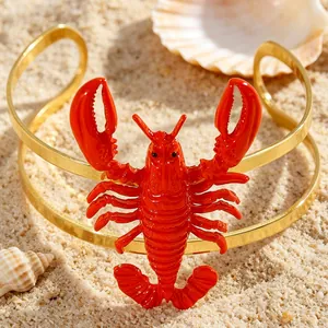 Close-up of a bold gold cuff bracelet with a vibrant red enameled lobster detail