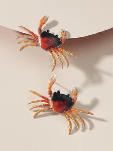 Close-up view of realistic orange and black crab pendant earrings for summer beach