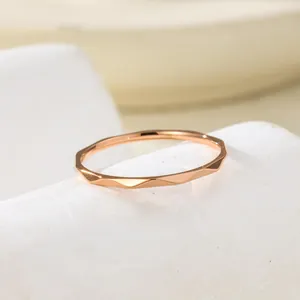Macro detail of a rose gold water ripple textured thin ring for women on a white stone base