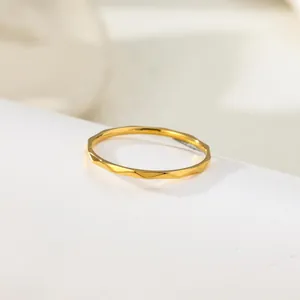Minimalist gold titanium steel ring with textured water wave pattern design for women.
