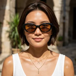 Occhiali da sole cat-eye alla moda con montatura nera e lenti color ambra sulla modella